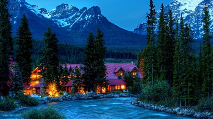 Lodge by a river with mountains and forest