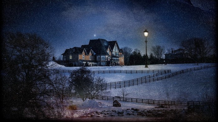 Snowy night with a large house and street lamp