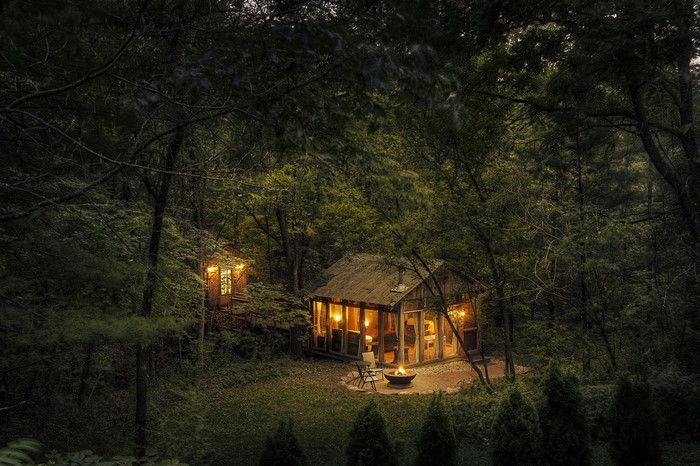 Cozy cabins in a dark forest with a campfire