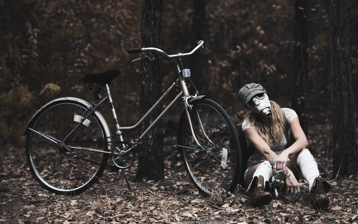 Woman in gas mask with bicycle in forest