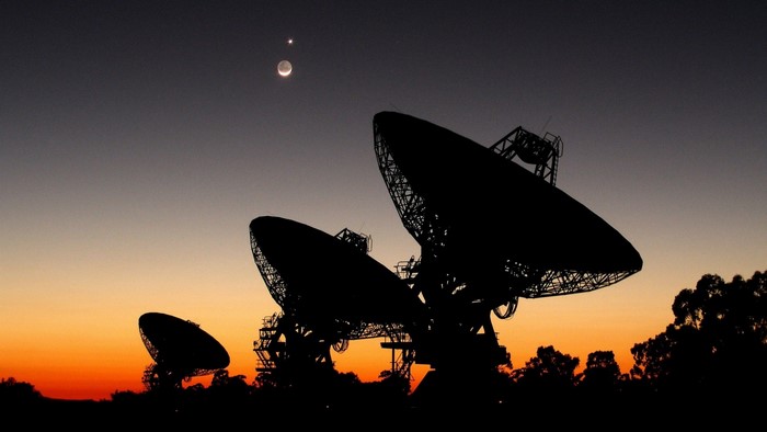 Radio telescopes at sunset with moon and Venus
