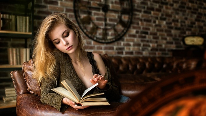 Woman reading a book in a leather chair