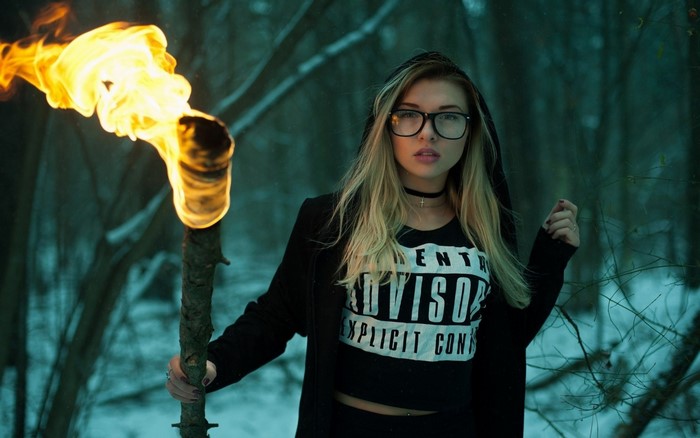Woman holding a flaming torch in a winter forest