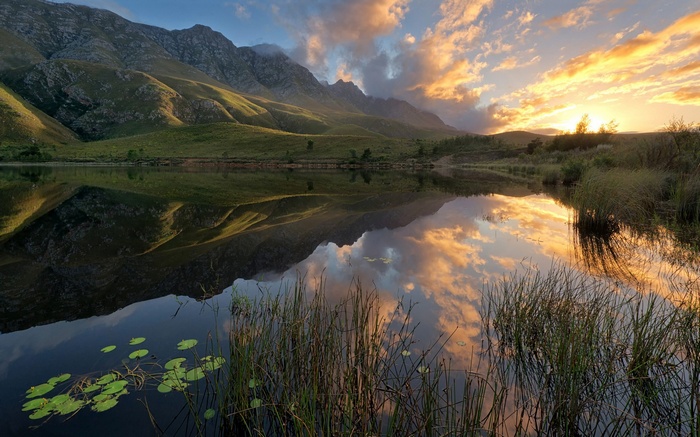 Mountain lake reflection at sunset with clouds