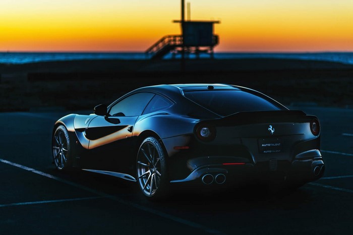 Black Ferrari parked by the beach at sunset