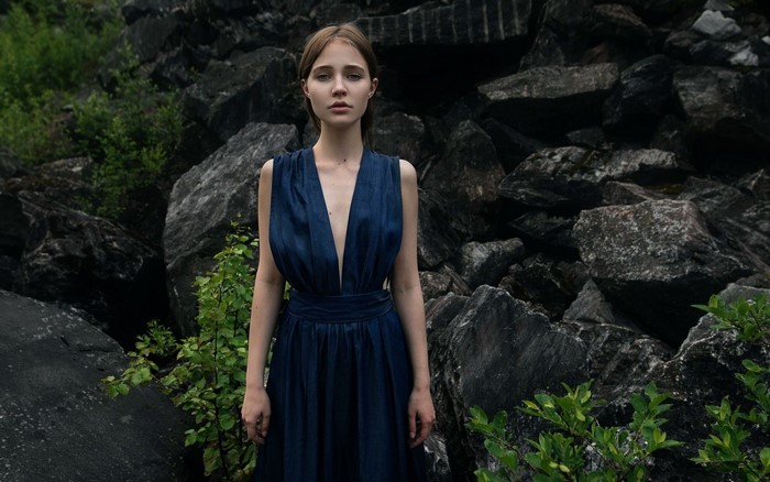 Woman in a blue dress standing in front of rocks