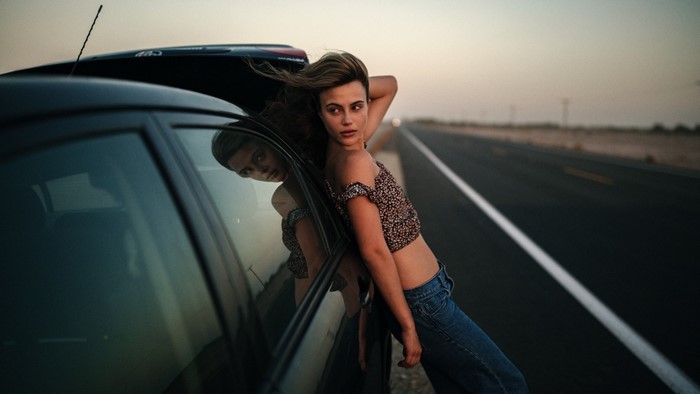 Woman leaning on car on desert road