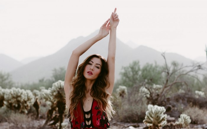 Asian woman with arms raised in desert landscape