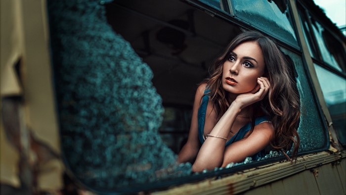 Woman looking out of a broken bus window