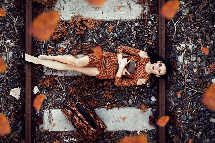 Woman lying on railway tracks with a book
