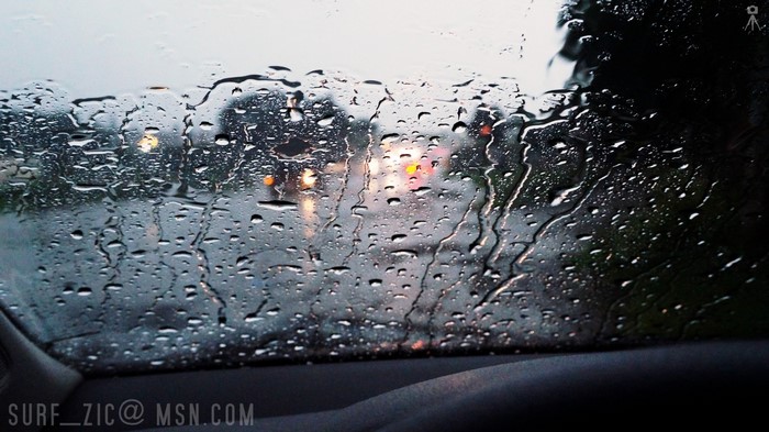 Raindrops on a car window with blurred lights