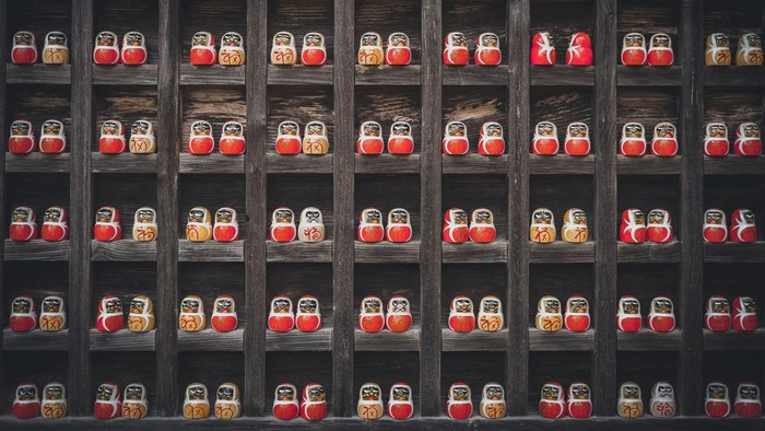Daruma dolls displayed on wooden shelves