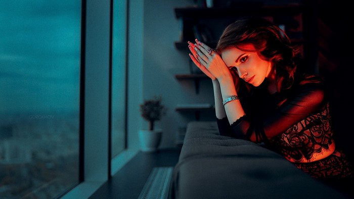 Woman by the window with red and blue light