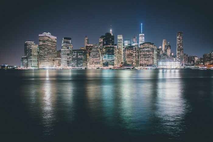 New York City skyline at night with water reflection