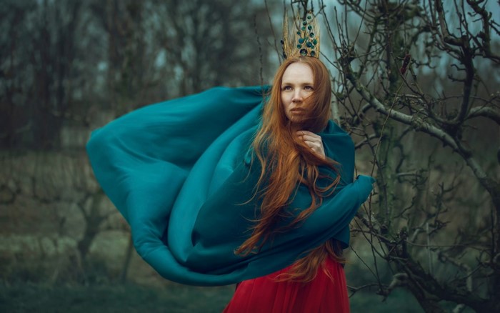 Woman with red hair and crown in a teal cloak