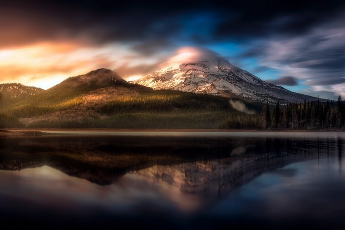 Snow-capped mountain reflected in a lake at sunset