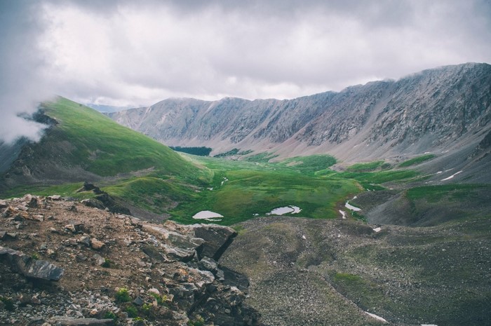 Mountain valley with lakes and green hills under cloudy sky