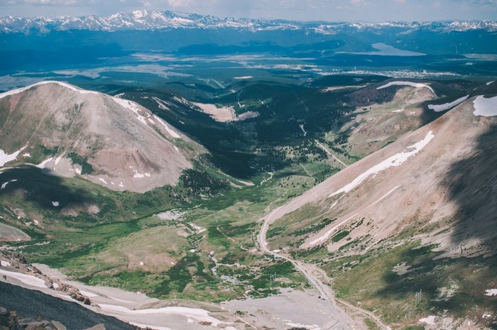 Aerial view of a mountain valley with snow-capped peaks in the distance