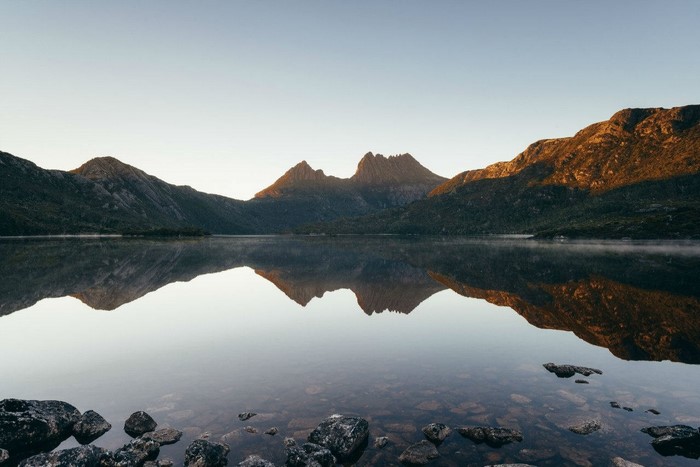 Mountain range reflected in a calm lake at sunrise