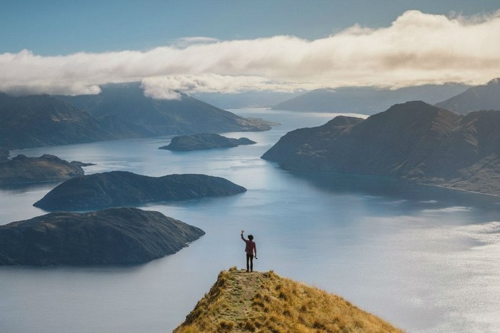 Person on mountain peak overlooking lake and mountains