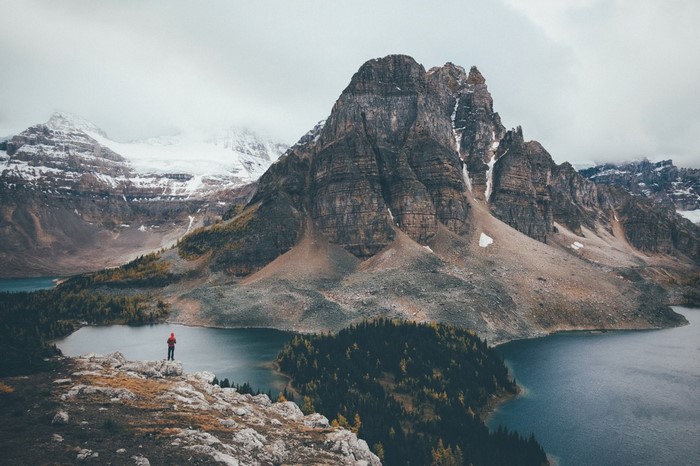 Person standing on a cliff overlooking a mountain lake