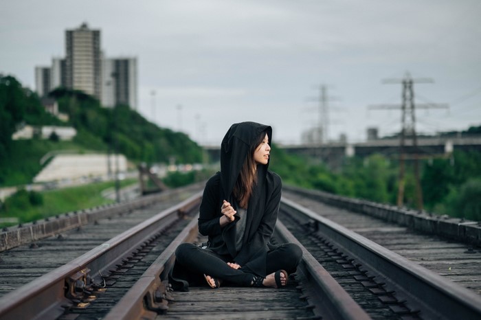 Woman sitting on train tracks