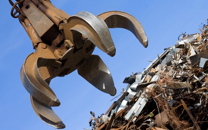 Scrap metal claw machine against blue sky