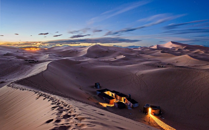 Desert camp at dusk with sand dunes