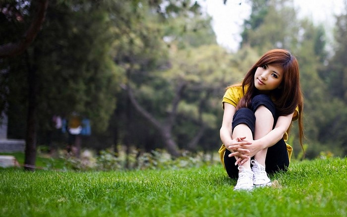 Young Asian woman sitting in a grassy park