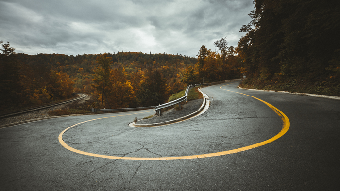 Winding road with railroad tracks in autumn