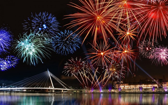 Fireworks over a bridge and cityscape at night