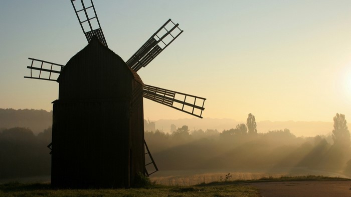 Silhouette of a windmill at sunrise with mist