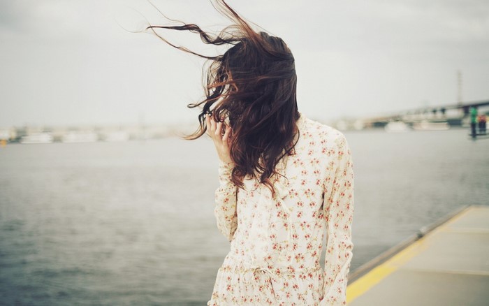 Woman in floral dress with windblown hair by the water