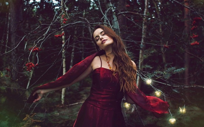 Woman in red dress in dark forest with berries