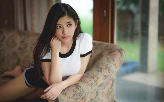 Thoughtful Woman Relaxing on Floral Couch