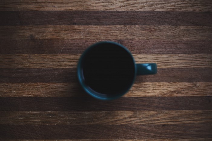 A dark mug of coffee on a wooden surface