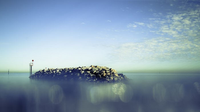 Rocky island with navigation marker in the sea