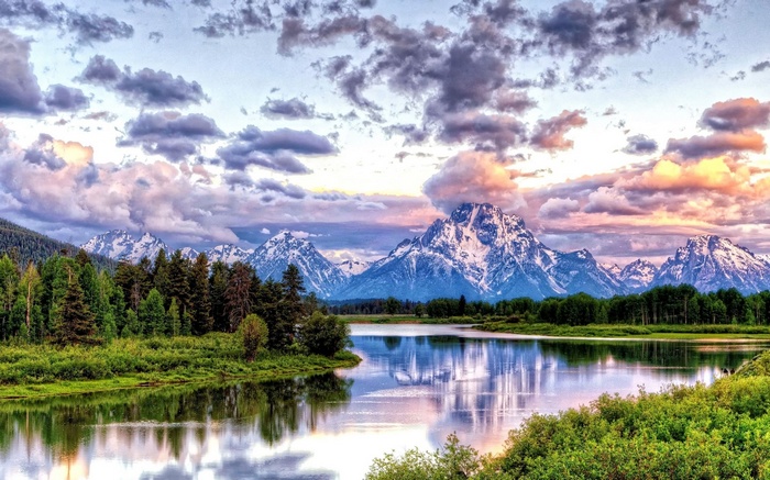 Snow-capped mountains reflected in a calm lake at sunset