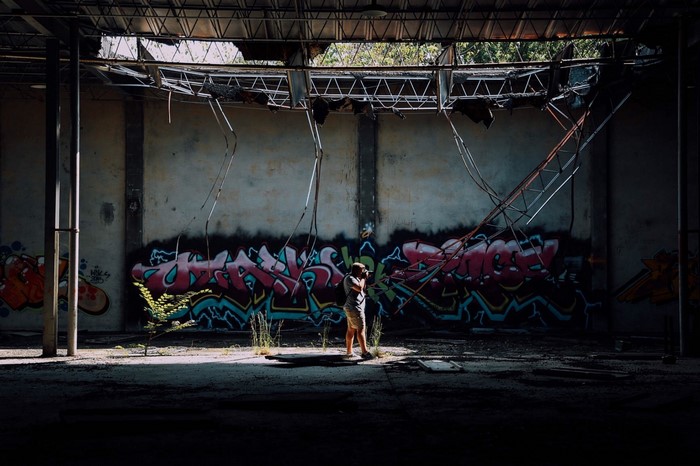 Person photographing graffiti in abandoned building