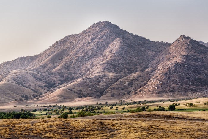Mountain landscape with dry grass fields and scattered trees