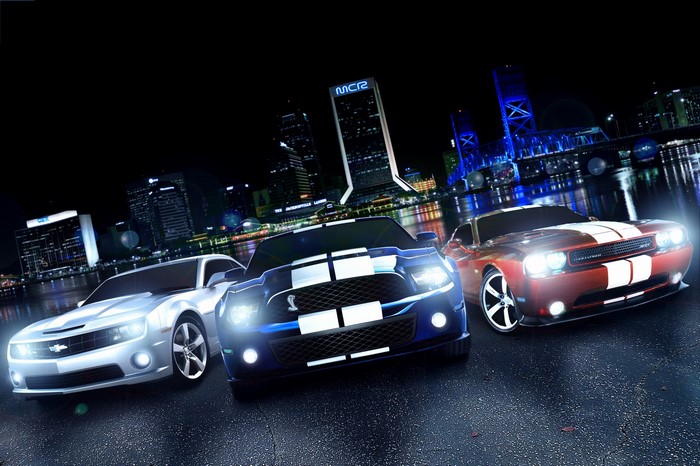 Three sports cars in a city at night