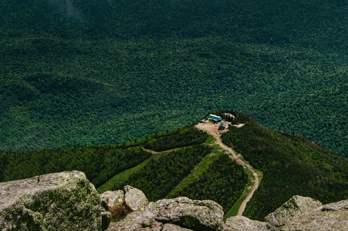 Mountain summit with buildings and forest below