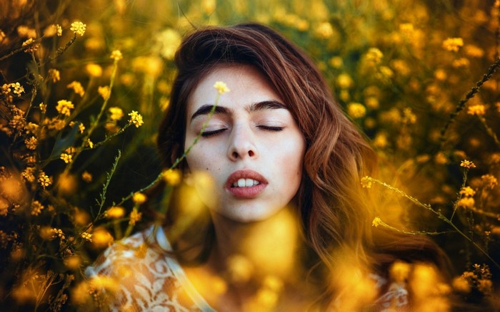 Woman with closed eyes in a field of yellow flowers