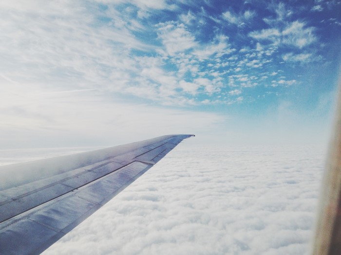 Airplane wing flying above clouds during the day