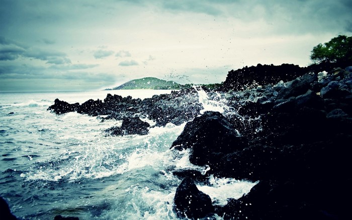 Waves crashing on dark rocks at dusk