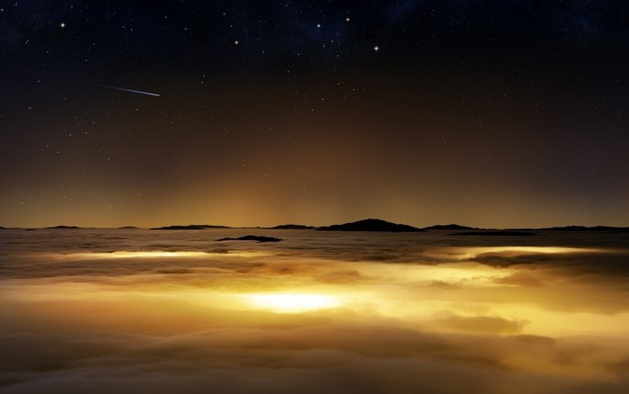 Night sky over clouds and mountains