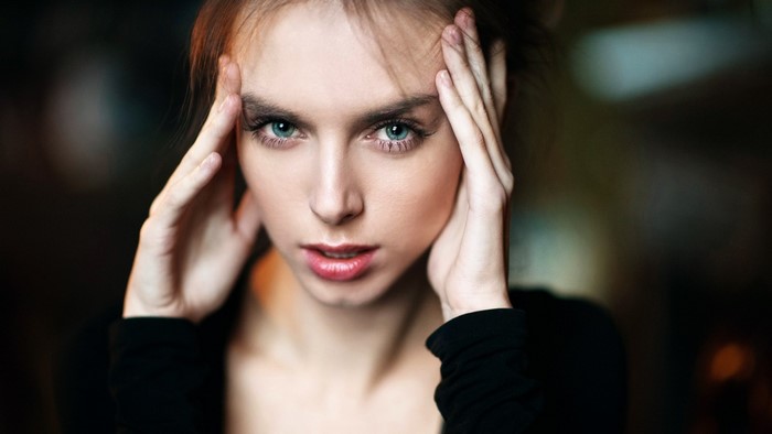 Model with hands on head, blue eyes, and black top
