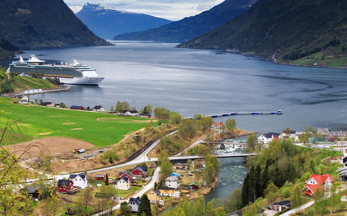 Cruise ship docked in a Norwegian fjord with a village