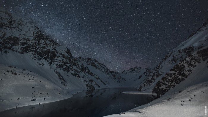 Snowy mountains and lake under starry night sky