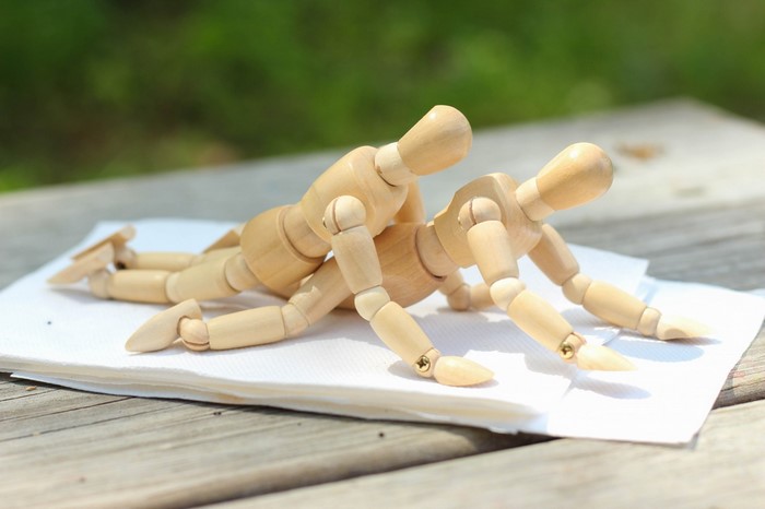 Two wooden mannequins in a sexual position on a napkin